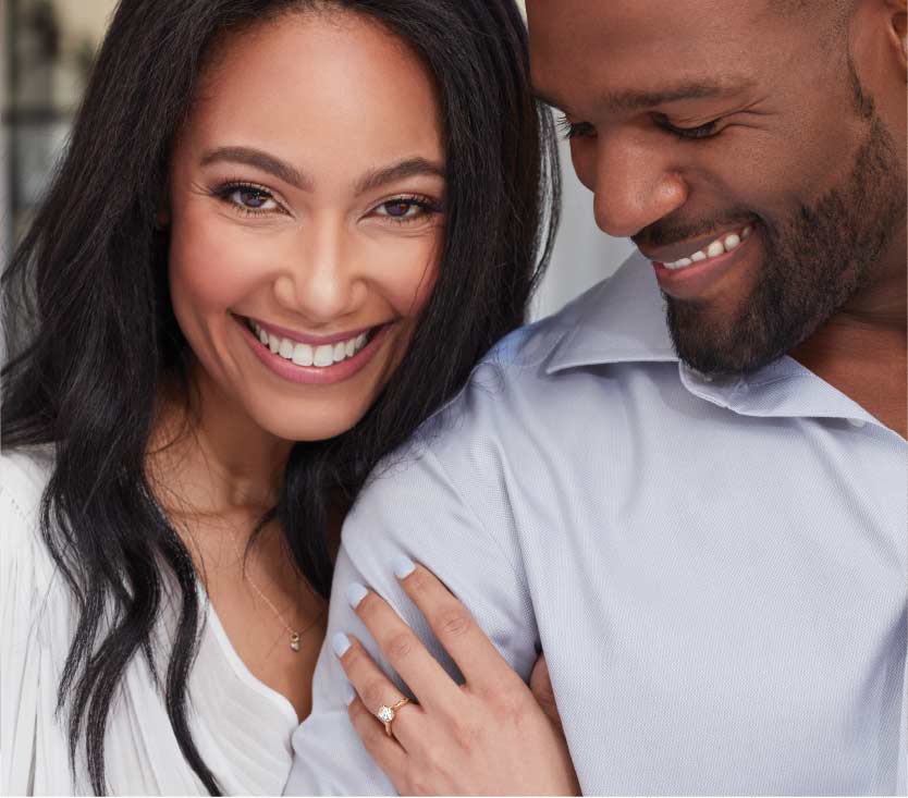 smiling woman with ring holding mans arm